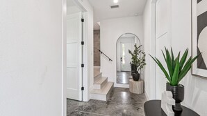 Ein moderner Flur mit Marmorboden, weißen Wänden und einer Treppe, die zu einem anderen Raum führt.