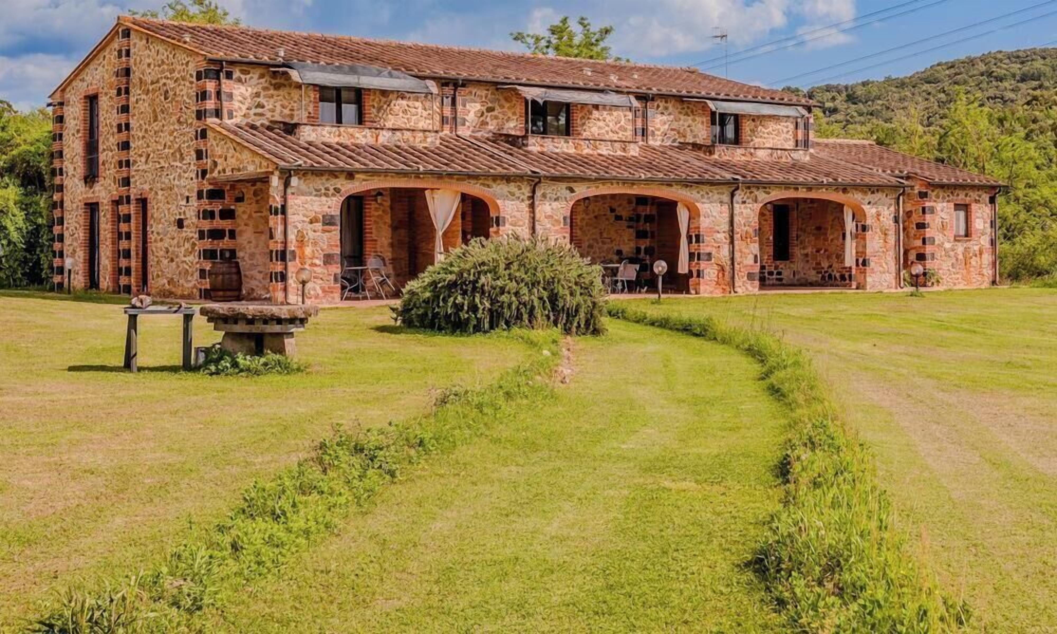 A stone building with multiple arches and a grassy lawn.