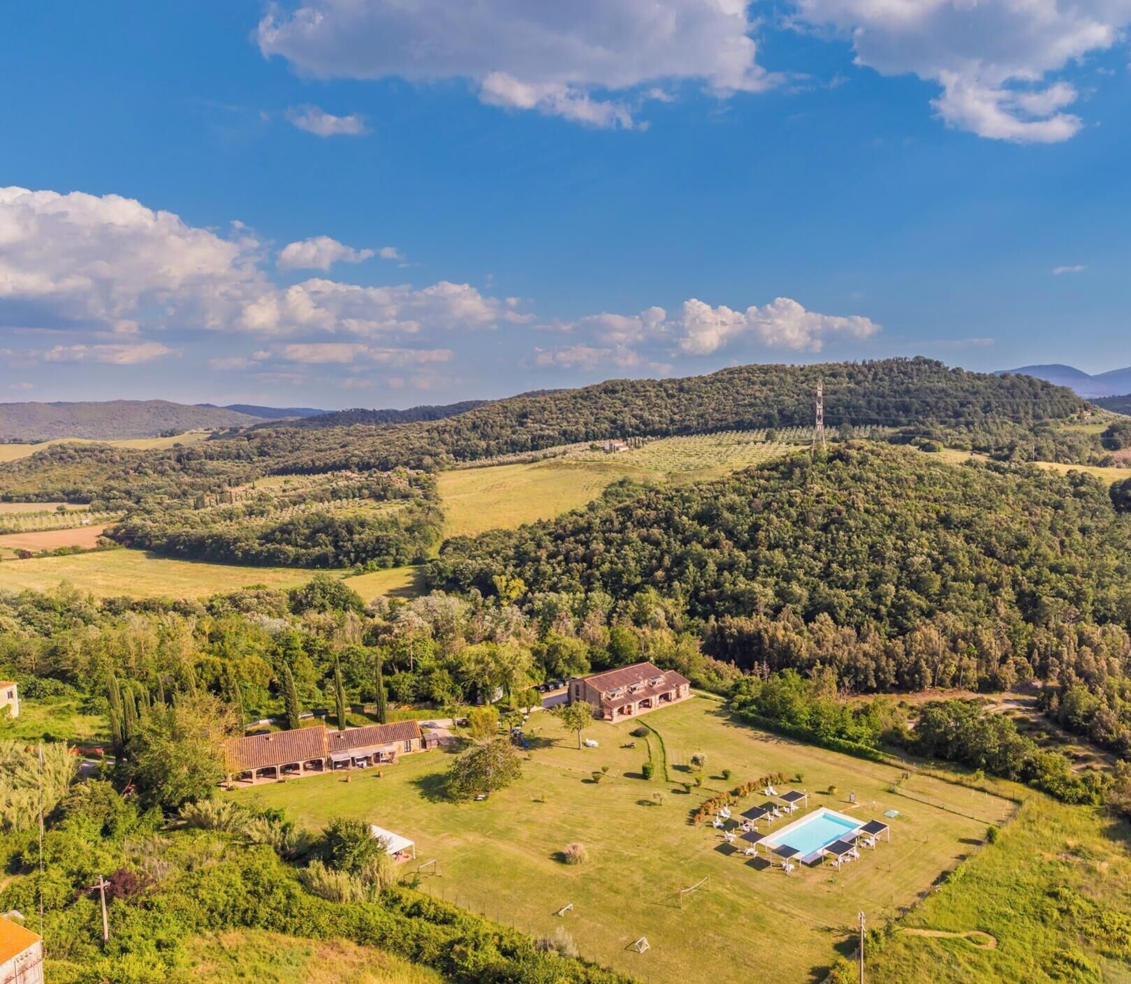 Paisaje rural con una edificación grande rodeada de árboles y campos.