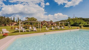 Ein Pool mit klarem Wasser, umgeben von weißen Liegestühlen und einer Pergola.