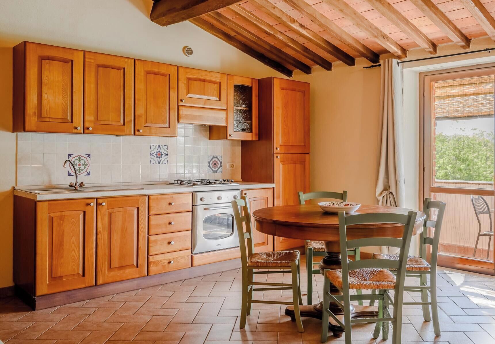 Una cocina con armarios de madera, estufa y una mesa de comedor con sillas.