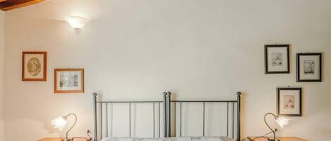A bedroom with a metal bed frame, two bedside tables with lamps, and framed pictures on the walls.