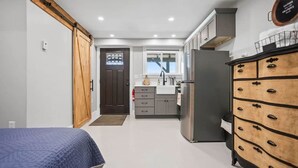 A compact kitchen with a refrigerator, cabinets, and a wooden dresser. - Raven Feather Retreat : Unit 2 (Liberty Township)