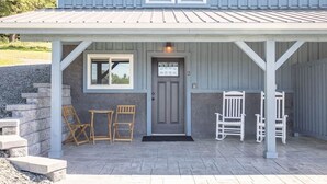 A covered porch with a grey door, two windows, and a small table with chairs. - Raven Feather Retreat : Unit 2 (Liberty Township)