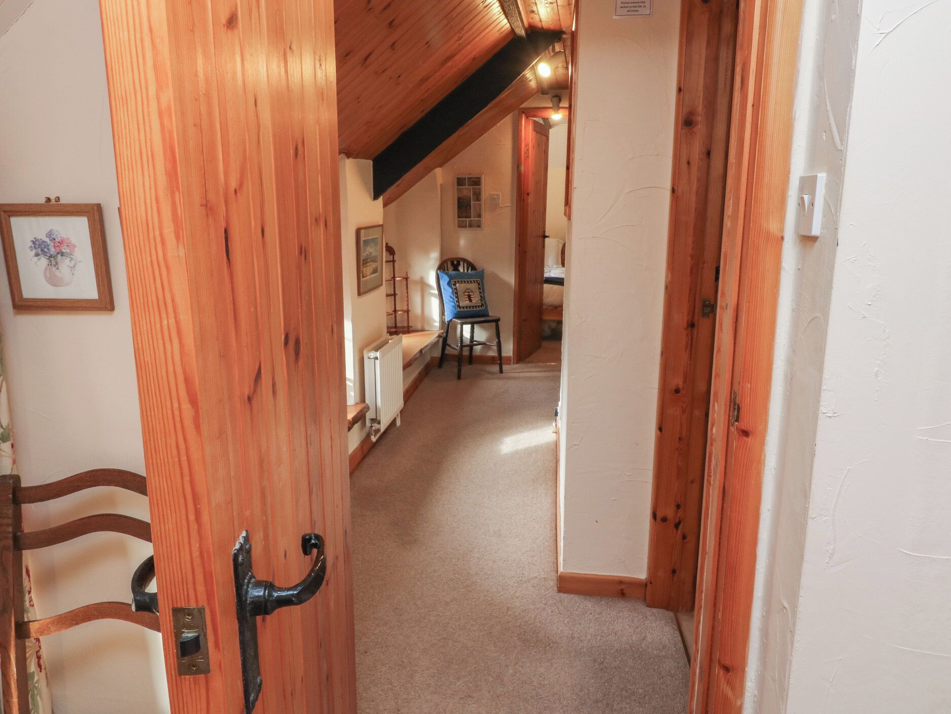 A narrow hallway with wooden walls and a sloped ceiling.