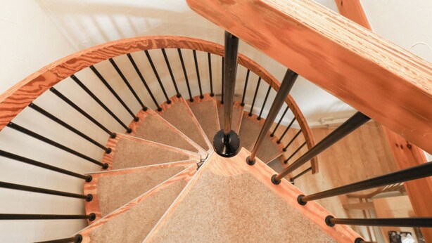 Una escalera de caracol con peldaños de madera y barandillas de metal.