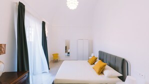 Camera d'albergo moderna con un letto grande, un comodino, una sedia, un armadio e uno specchio.
