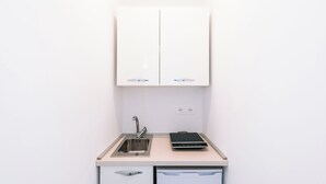 Una cucina compatta con lavello, lavastoviglie e un piano cottura a induzione portatile.