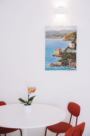 A dining area with a round table, red chairs, and a potted orchid. - Modern, centrally located apartment with all the amenities and an outdoor area (Scala)