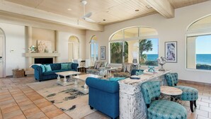 A spacious living room with a large window, a fireplace, and a ceiling fan.