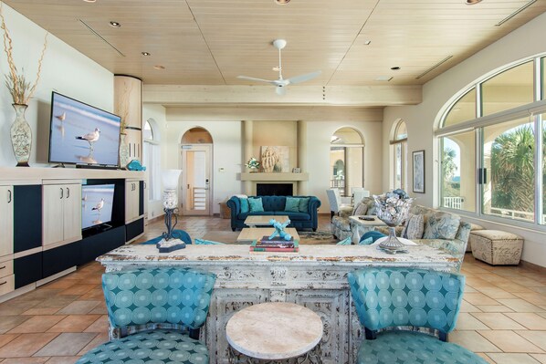A spacious living area with a large TV, a fireplace, and a cozy seating arrangement. - Expansive 10 BR Oceanfront Estate with Infinity Pool, Theater & Grand Spaces (Indian Beach)