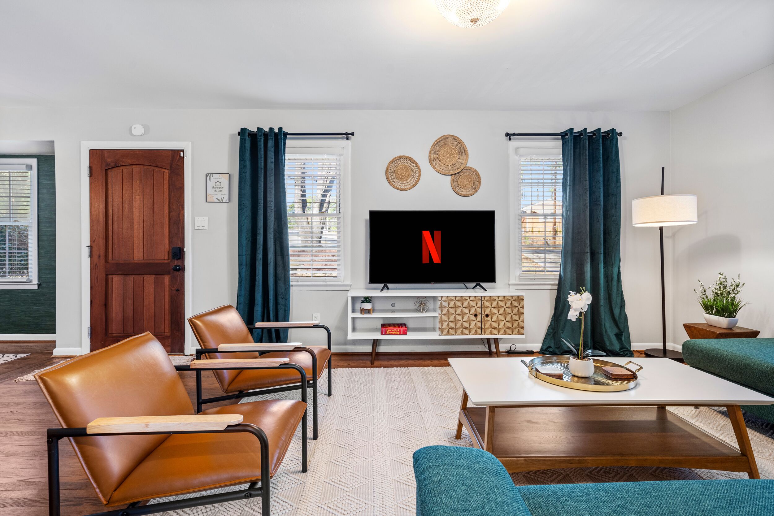 Un salon avec un téléviseur affichant le logo de Netflix, des fauteuils en cuir, une table basse et un canapé.