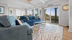 Ein Wohnzimmer mit einem blauen Sofa, einem Holztisch und einem gemusterten Teppich.