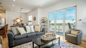 A living room with a sofa, armchair, coffee table, and a large window with a view.