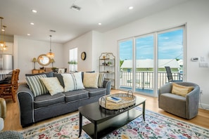 A living room with a sofa, armchair, coffee table, and a large window with a view.