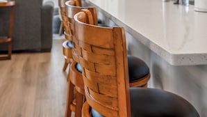 A modern kitchen with a long island, wooden chairs, and pendant lighting.