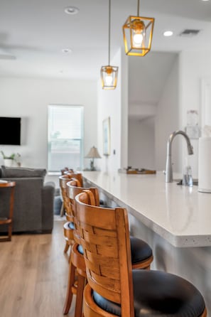 Una cocina moderna con una isla grande, sillas de madera e iluminación colgante.