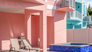 A swimming pool with a tiled edge, lounge chairs, and a building with balconies.
