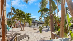 Un espace extérieur de style tropical, agrémenté de palmiers, d’une piscine et de chaises longues.
