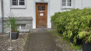 Um edifício com porta de madeira, uma pequena janela e um vaso de planta em frente.