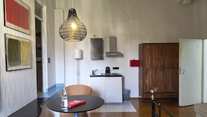 Um espaço de estar compacto com cozinha americana, área de jantar com mesa e cadeiras, e um guarda-roupa espaçoso.