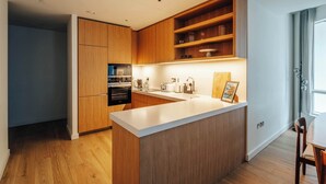Eine moderne Küche mit Holzausstattung, einer weißen Arbeitsplatte und integrierten Regalen.