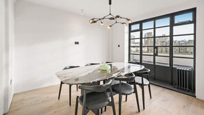 Een moderne eetruimte met een marmeren tafel, zwarte stoelen en een bijzondere kroonluchter.