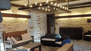 Un interior acogedor con paredes de piedra, chimenea y una zona de estar con sofás y una mesa de centro.