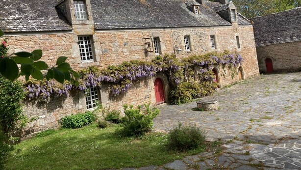 Un edificio de piedra con puerta roja, una ventana pequeña y una escalera de piedra que lleva a él.