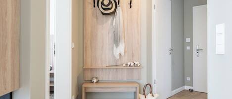 A hallway with a wooden bench, a coat rack, and a door.
