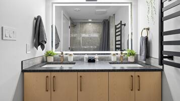 A modern bathroom with two sinks, wooden cabinets, and a large mirror.