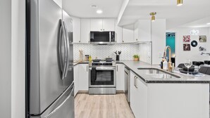 A modern kitchen with stainless steel appliances, a herringbone tile backsplash, and a granite countertop.