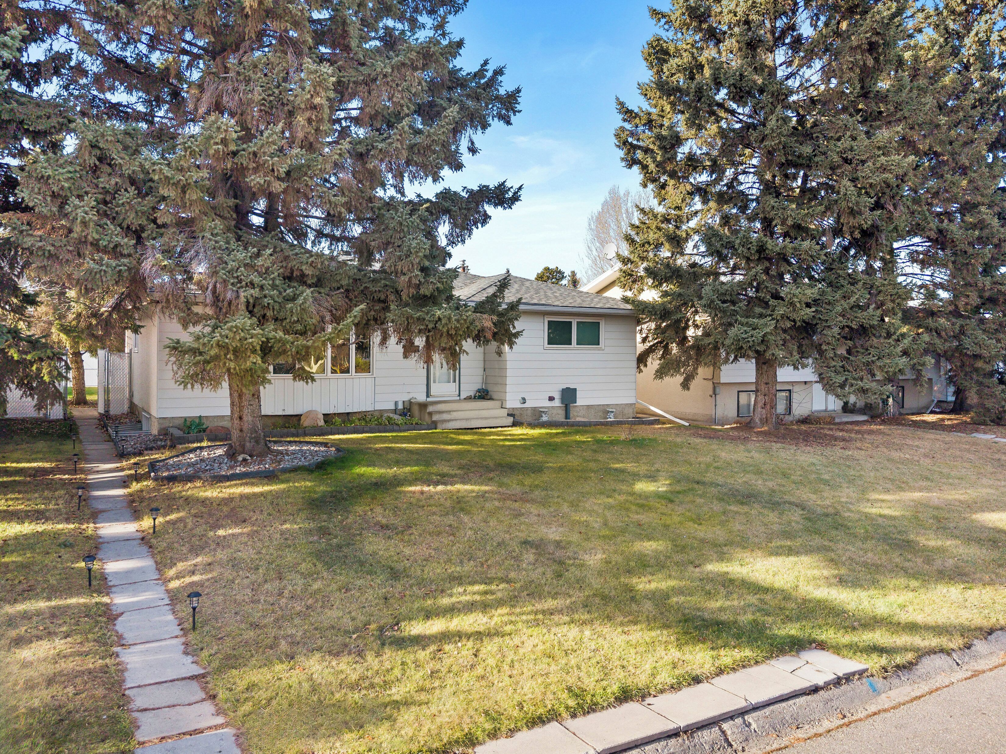 A single-story mobile home with a front yard, a pathway leading to the entrance, and a small porch area.