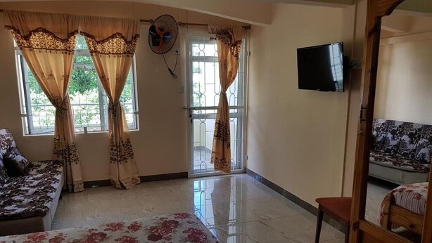 A room with a bed, a sofa, a TV, and a window with curtains. - Pereybere Beach Apartments: Studio with Balcony (Pereybere)