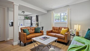 A modern living room with two leather sofas, a coffee table, and a view of the kitchen.