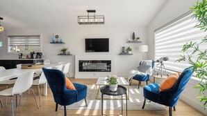 A modern living room with a fireplace, blue armchairs, a dining area, and a TV. - Perfect for families & groups seeking comfort, games & style in Edmonton (Edmonton)