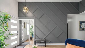 A modern living room with a geometric wall design, a blue armchair, a small bench, and a potted plant. - Perfect for families & groups seeking comfort, games & style in Edmonton (Edmonton)