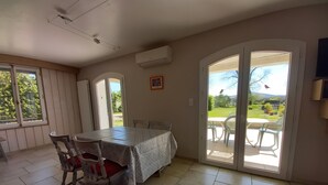 Un comedor con mesa y sillas, un patio corredizo de vidrio que da a un patio exterior, y un ventilador de techo.