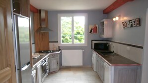 Una cocina con ventana, microondas y refrigerador.