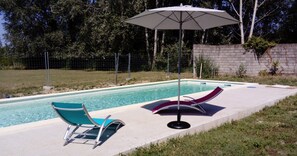 Une piscine avec deux chaises longues et un parasol de patio.