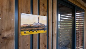 Una pared de madera con un cuadro enmarcado de un faro y ovejas.