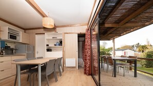 Una cocina moderna con electrodomésticos integrados, un comedor con mesa y sillas de madera, y una terraza con mobiliario exterior.