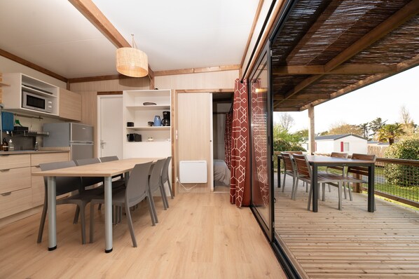 A modern kitchen with built-in appliances, a dining area with a wooden table and chairs, and a deck with outdoor seating.