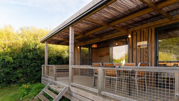 Una terraza de madera con mobiliario exterior y un área techada.