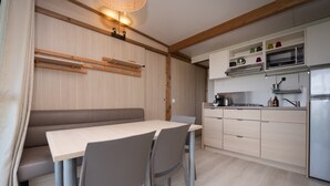 Une cuisine moderne avec un banc en bois et une table à manger, des placards intégrés et un four à micro-ondes.