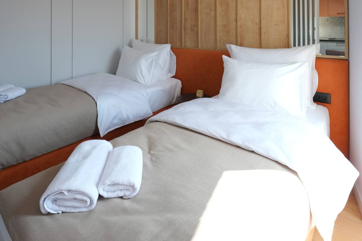 Una habitación de hotel moderna con dos camas, un espejo grande y una pared decorativa de madera.