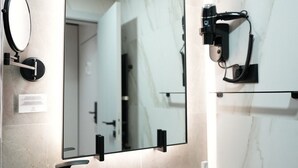 A modern bathroom with a black sink, a large mirror, and a camera mounted on the wall.