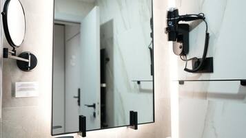A modern bathroom with a black sink, a large mirror, and a camera mounted on the wall.
