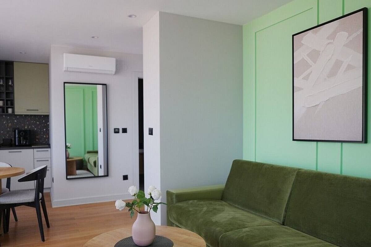 Una sala de estar moderna con un sofá verde, una mesa de centro redonda de madera y una alfombra gris.