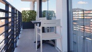 A balcony with a table and chairs, large windows, and a view of the cityscape.